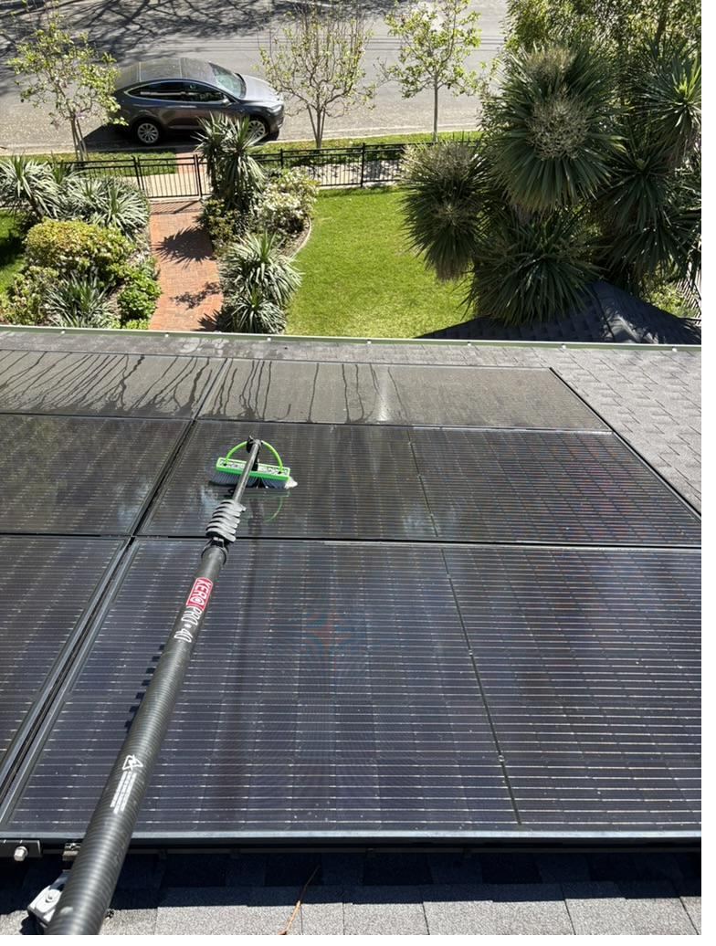 Cleaning a rooftop solar array with a soft brush on a water-fed pole, Peninsula home