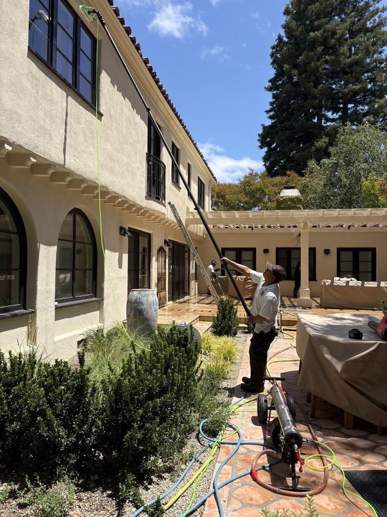 Nick's technician cleaning second-story windows with a water-fed pole on a Mediterranean estate